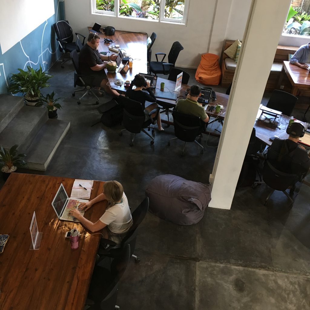 a group of people sitting at tables with laptops