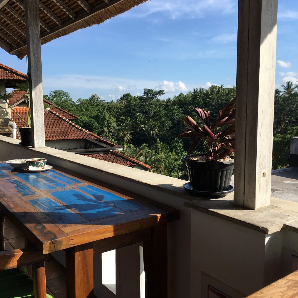 a table on a balcony with a view of trees and blue sky