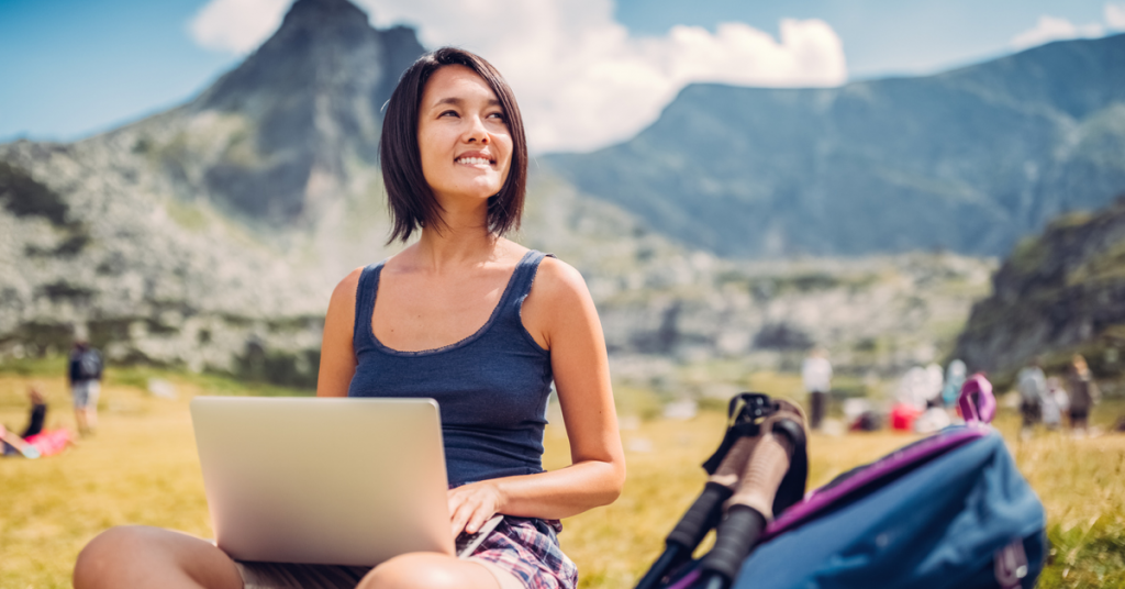 a woman sitting in a field with a laptop