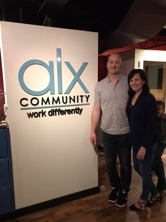 a man and woman standing next to a sign