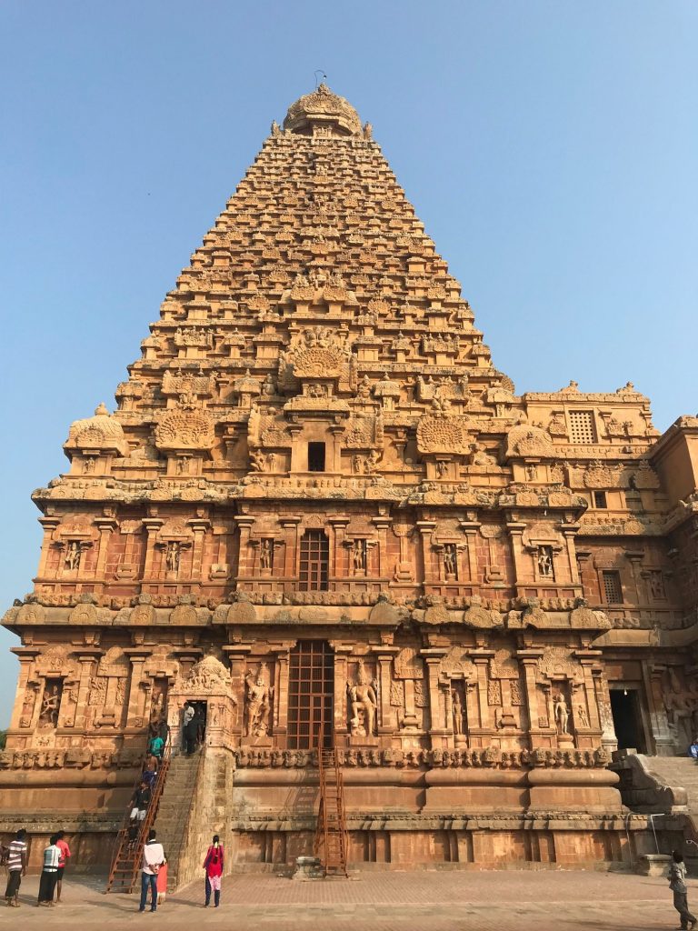 a large stone building with many carvings with Brihadeeswarar Temple in the background