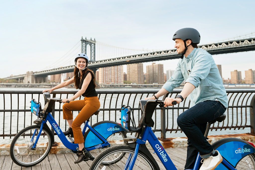a man and woman riding bicycles on a bridge