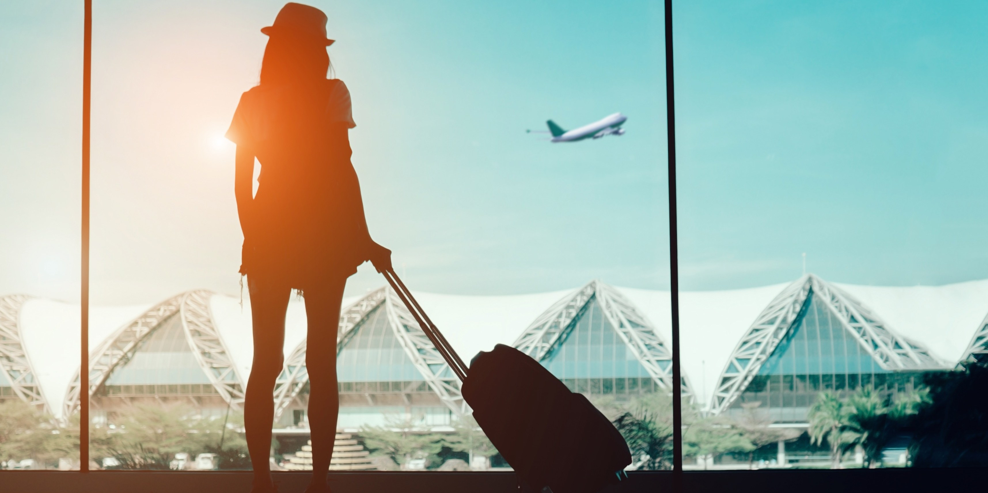 a woman with a hat and luggage in front of a window