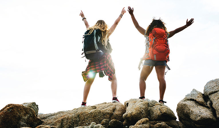 two women with backpacks on top of rocks