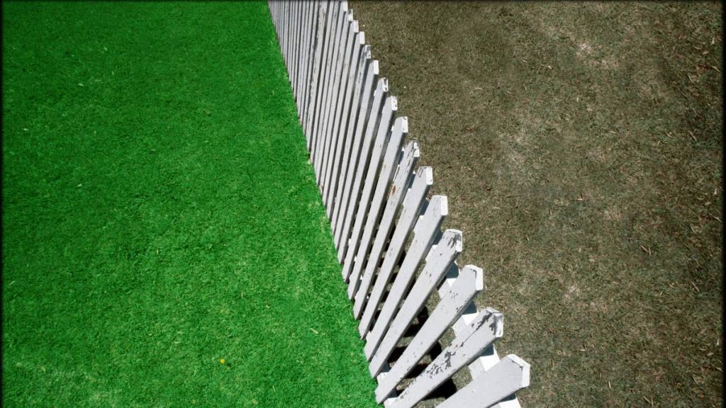a white picket fence next to a green grass lawn