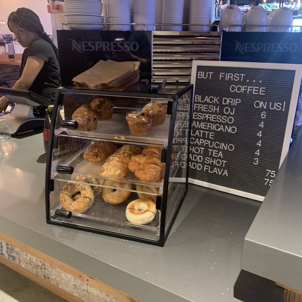 a coffee shop counter with a sign and pastries