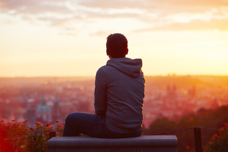 a person sitting on a bench looking at a city