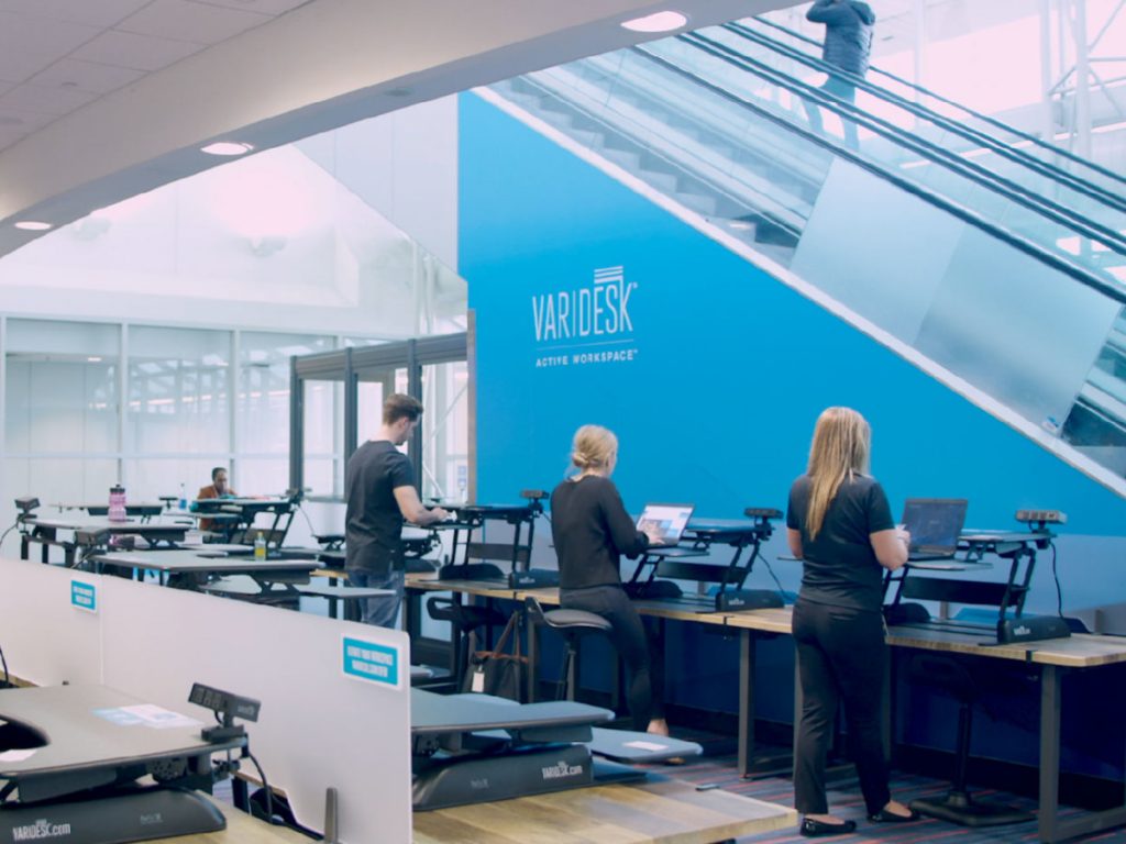 people working at tables in a room with escalators