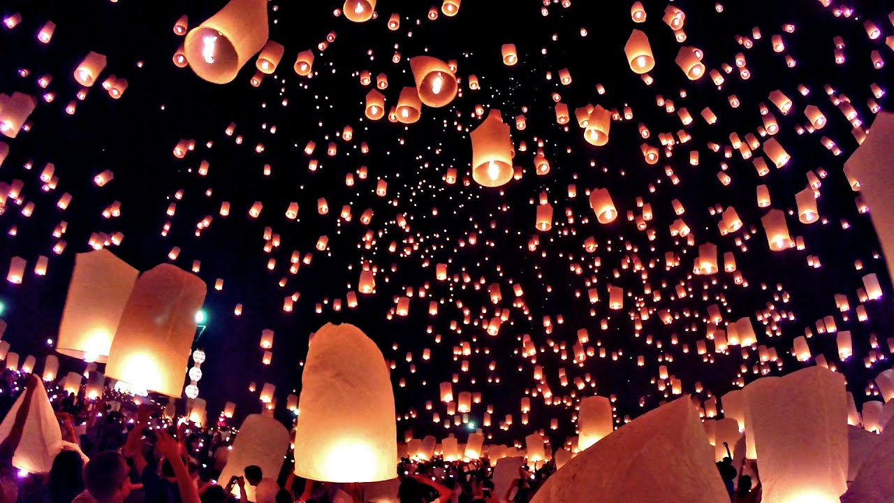 a group of people flying lanterns in the sky