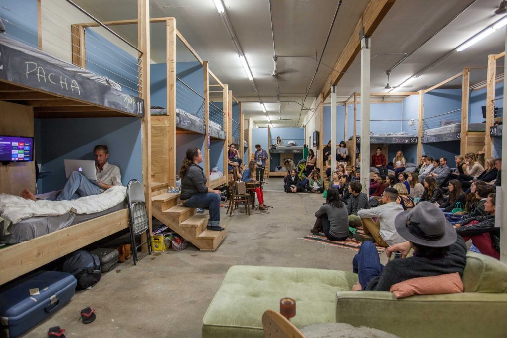 a group of people sitting in a room with bunk beds