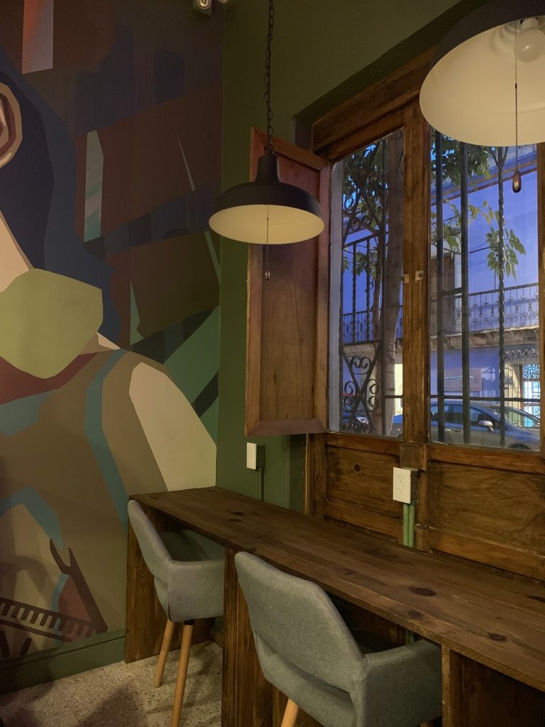 a room with a table and chairs and a window with a mural on the wall