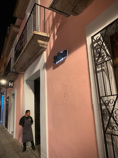 a man standing in front of a pink building