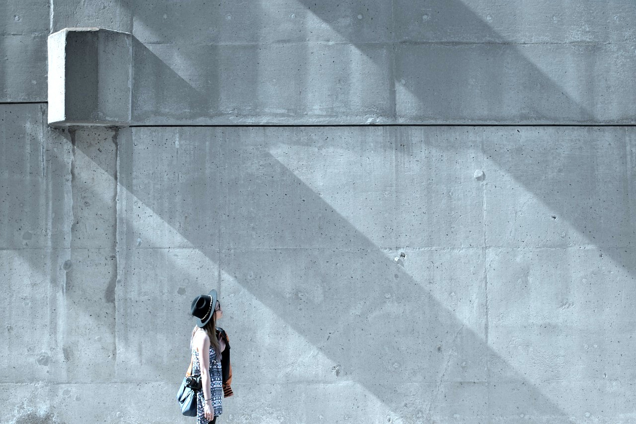a woman standing in front of a concrete wall