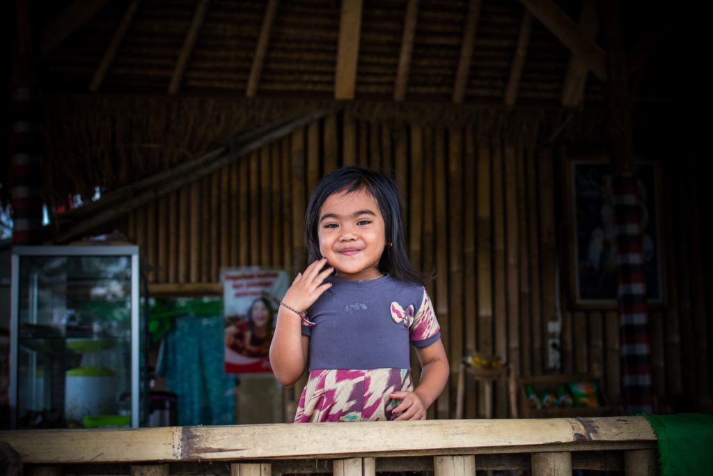 a girl standing in front of a wooden fence