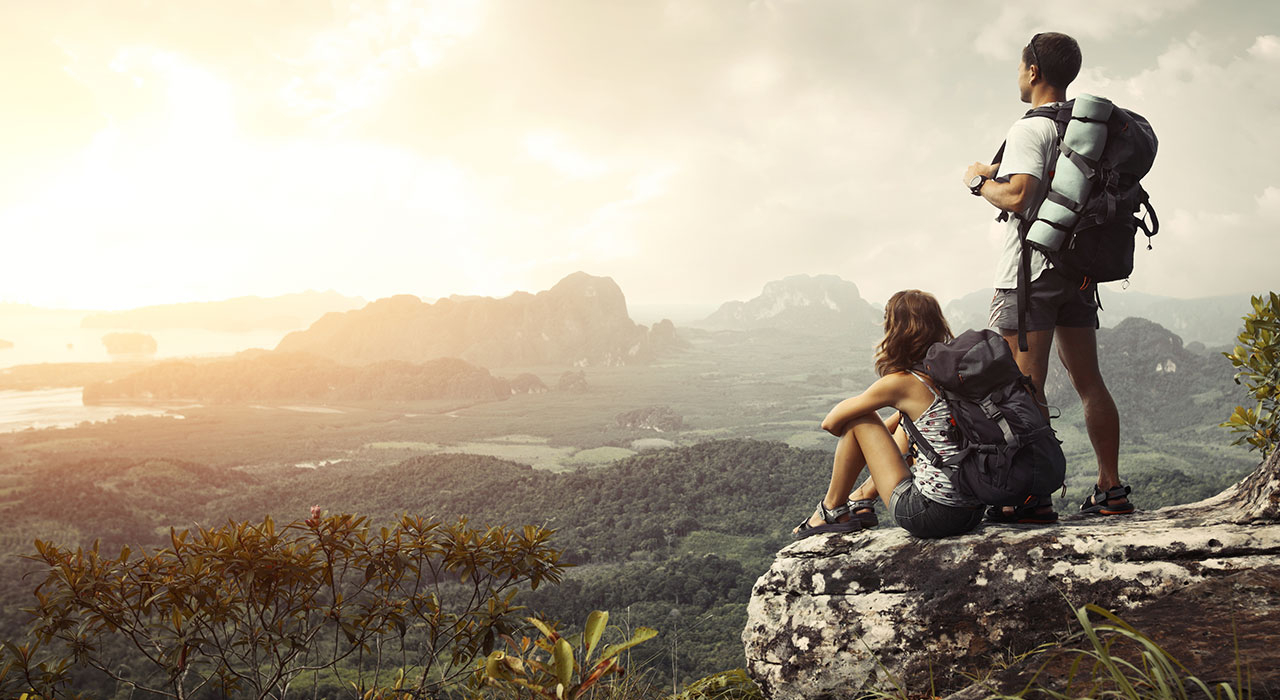 a couple of people sitting on a rock looking at a valley