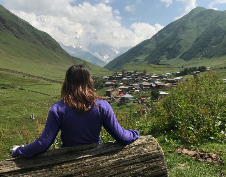 a woman sitting on a bench overlooking a town