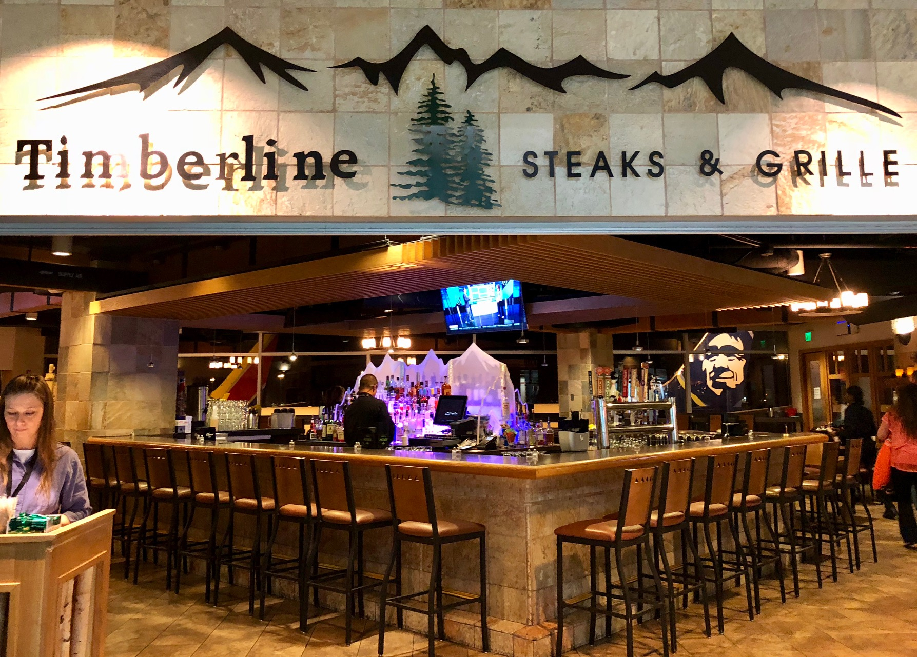 a bar with chairs and a sign