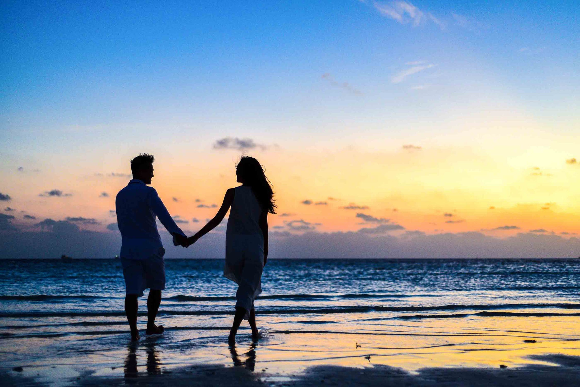 a man and woman holding hands on a beach
