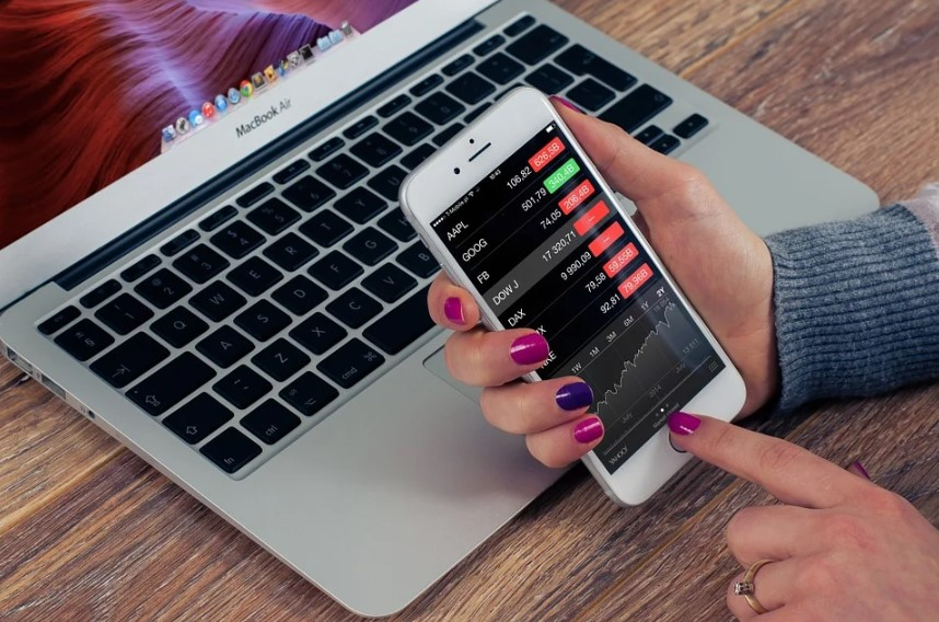 a person holding a phone in front of a laptop