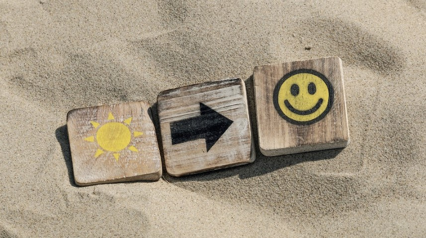 a wooden blocks with a smiley face and arrow on sand