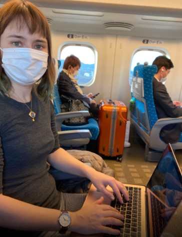 a woman wearing a mask and using a laptop on a plane