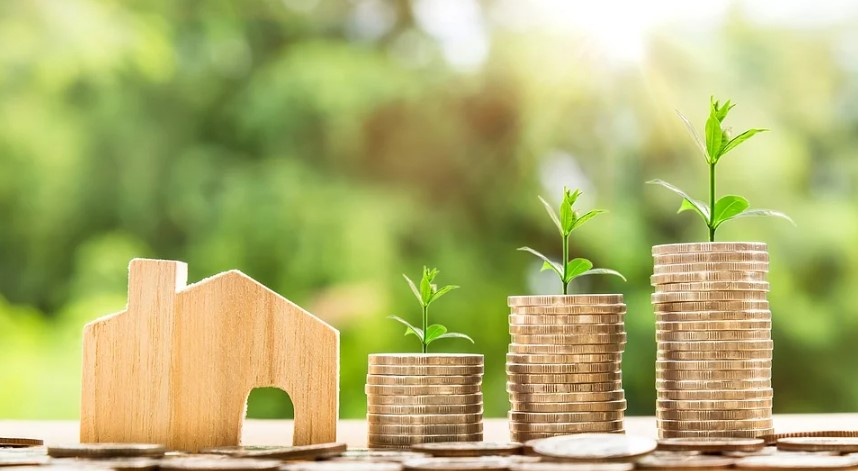 a stack of coins with a small house and a small plant growing on them