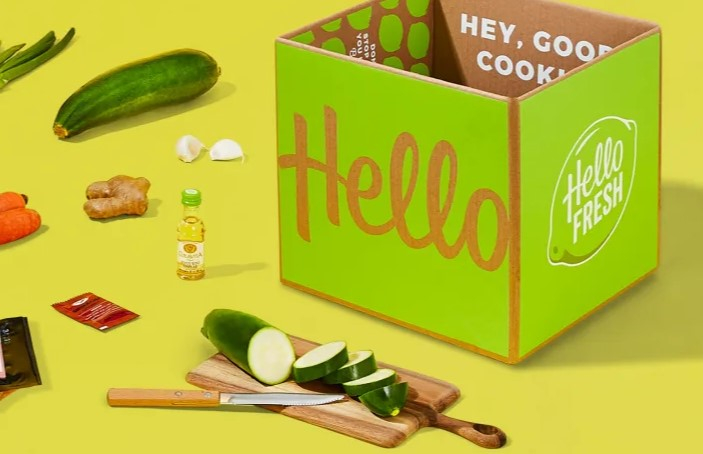 a box with cucumbers and a knife on a yellow surface