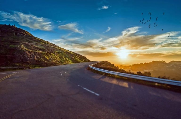 a road with a hill and a sunset