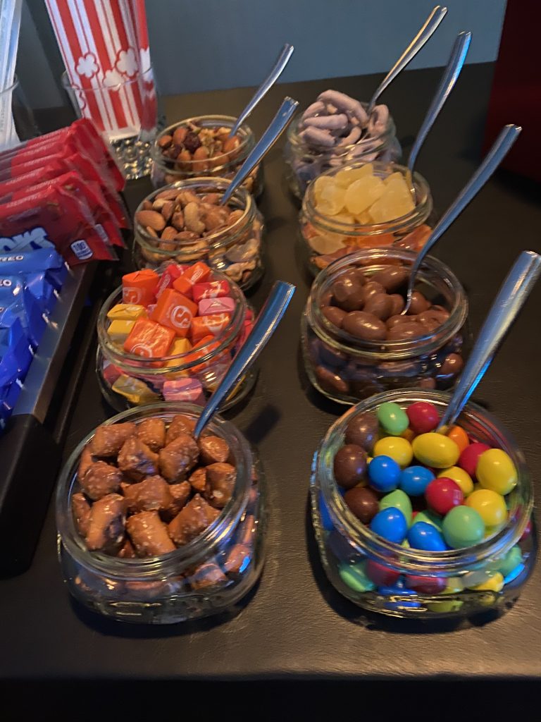 a group of glass jars with different colored candies and spoons