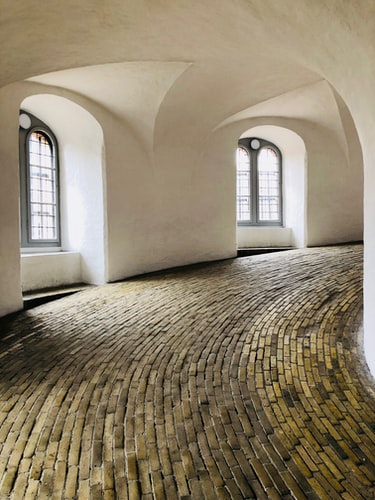 a curved brick floor in a room with arched windows