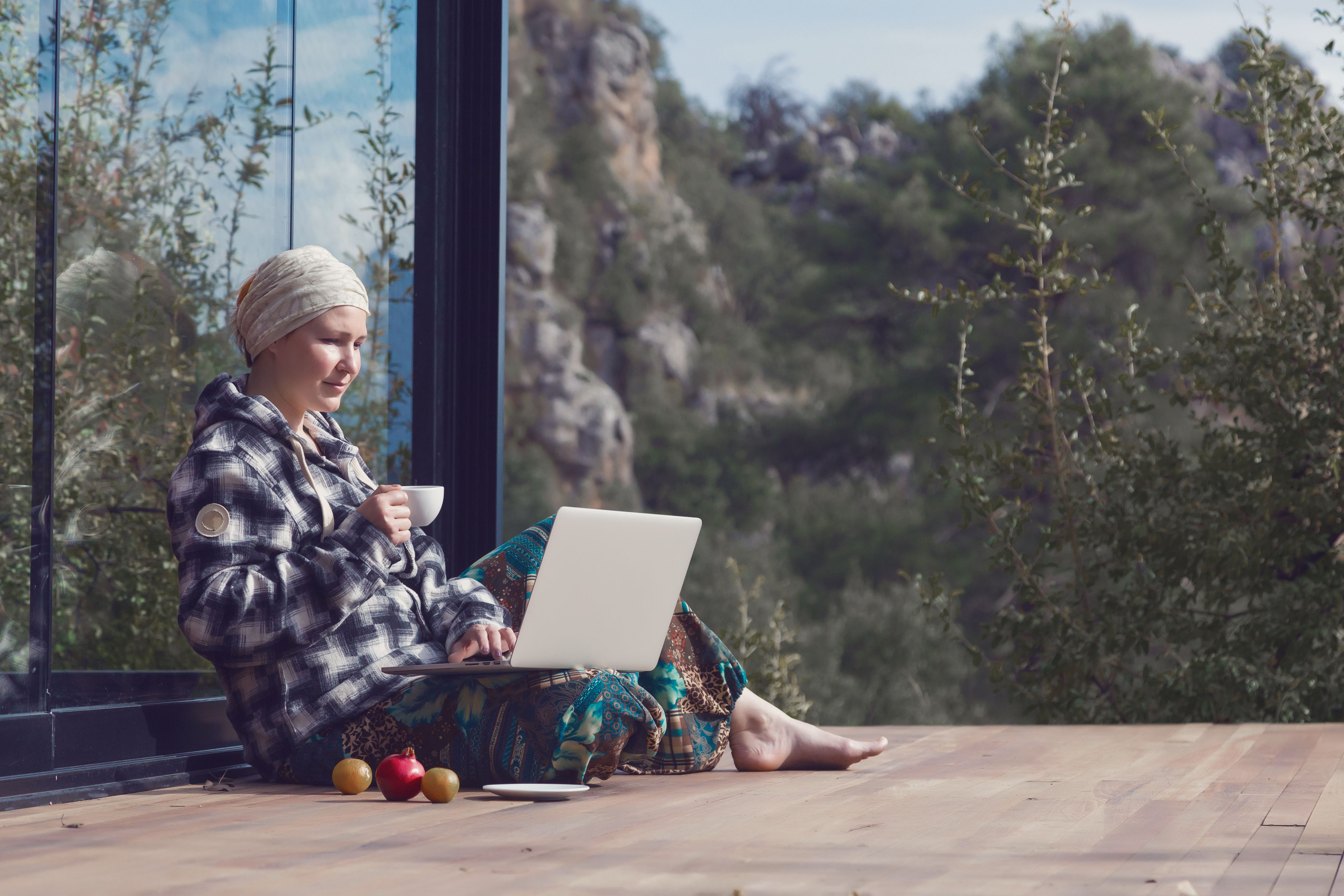 a woman sitting on a porch with a laptop and fruit