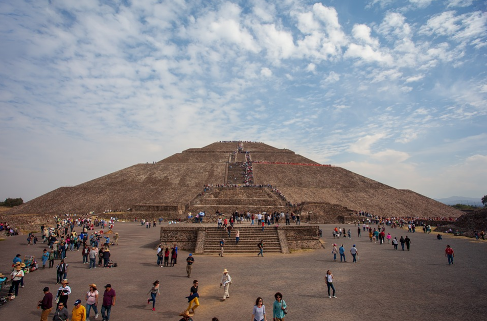 a group of people walking around a pyramid with Pyramid of the Sun in the background