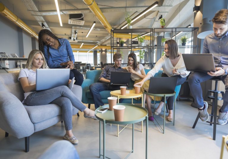 a group of people sitting around a table with laptops