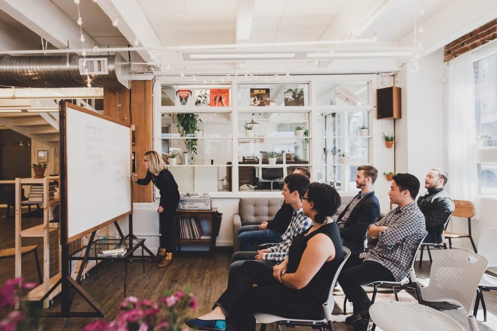 a group of people sitting in chairs and a whiteboard