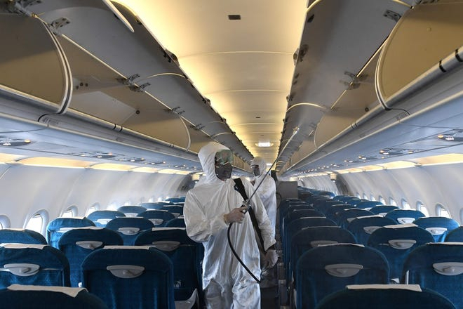 people in hazmat suits on an airplane