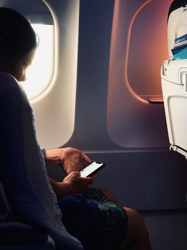 a woman sitting on a plane looking at her phone