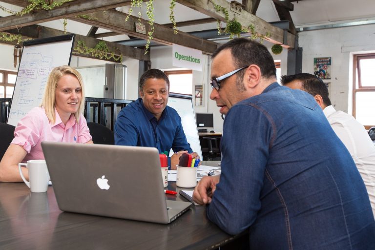 a group of people sitting at a table with laptops