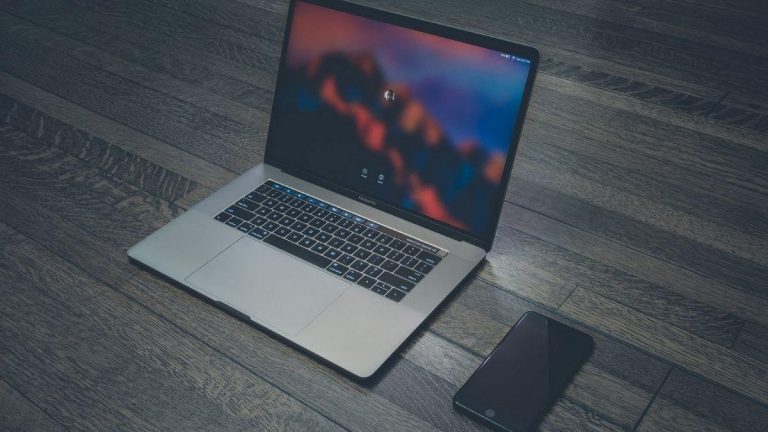 a laptop and a cell phone on a wood floor